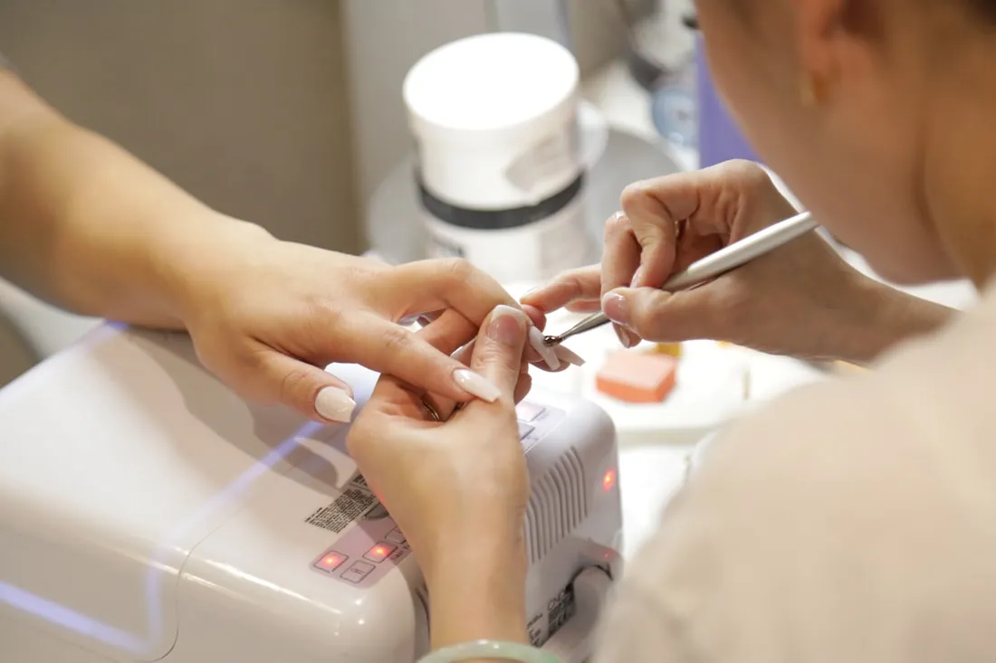 Nail technician carefully applying a gel manicure to a client's hand
