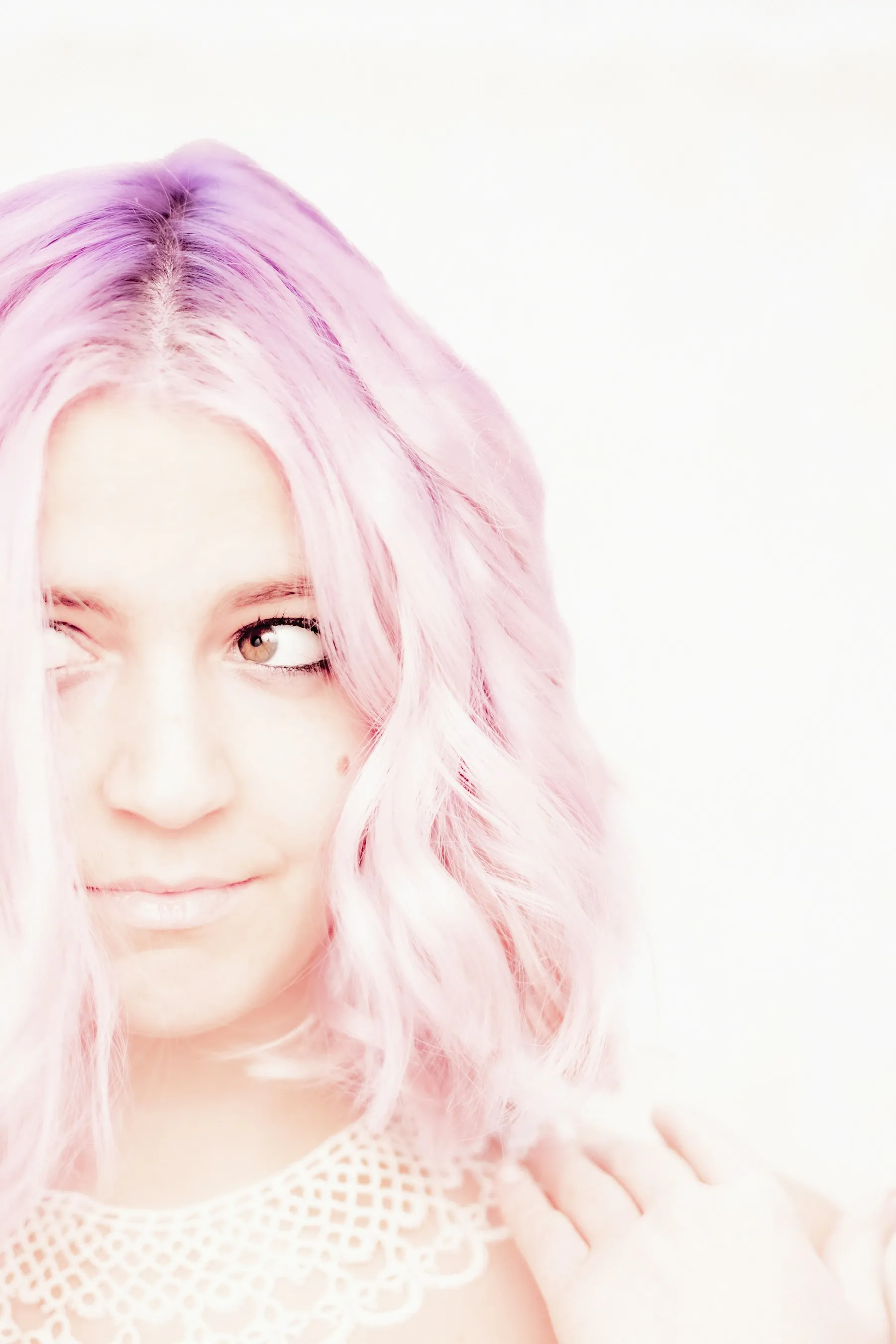 Salon client with soft pastel pink and lavender colored hair, smiling gently