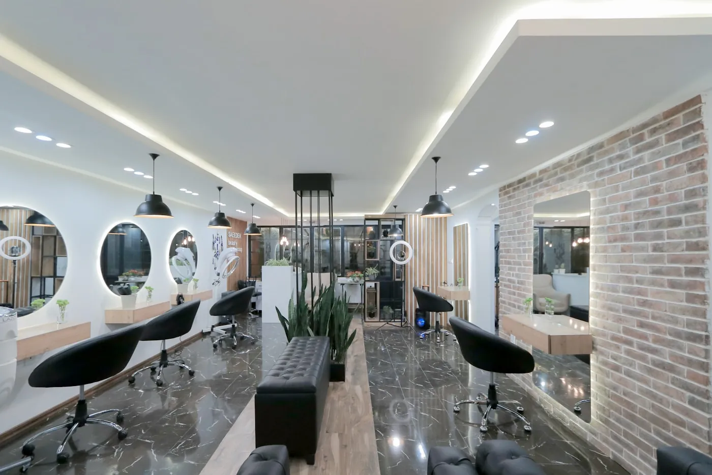 Bright, modern salon interior with styling chairs, round mirrors and a brick accent wall
